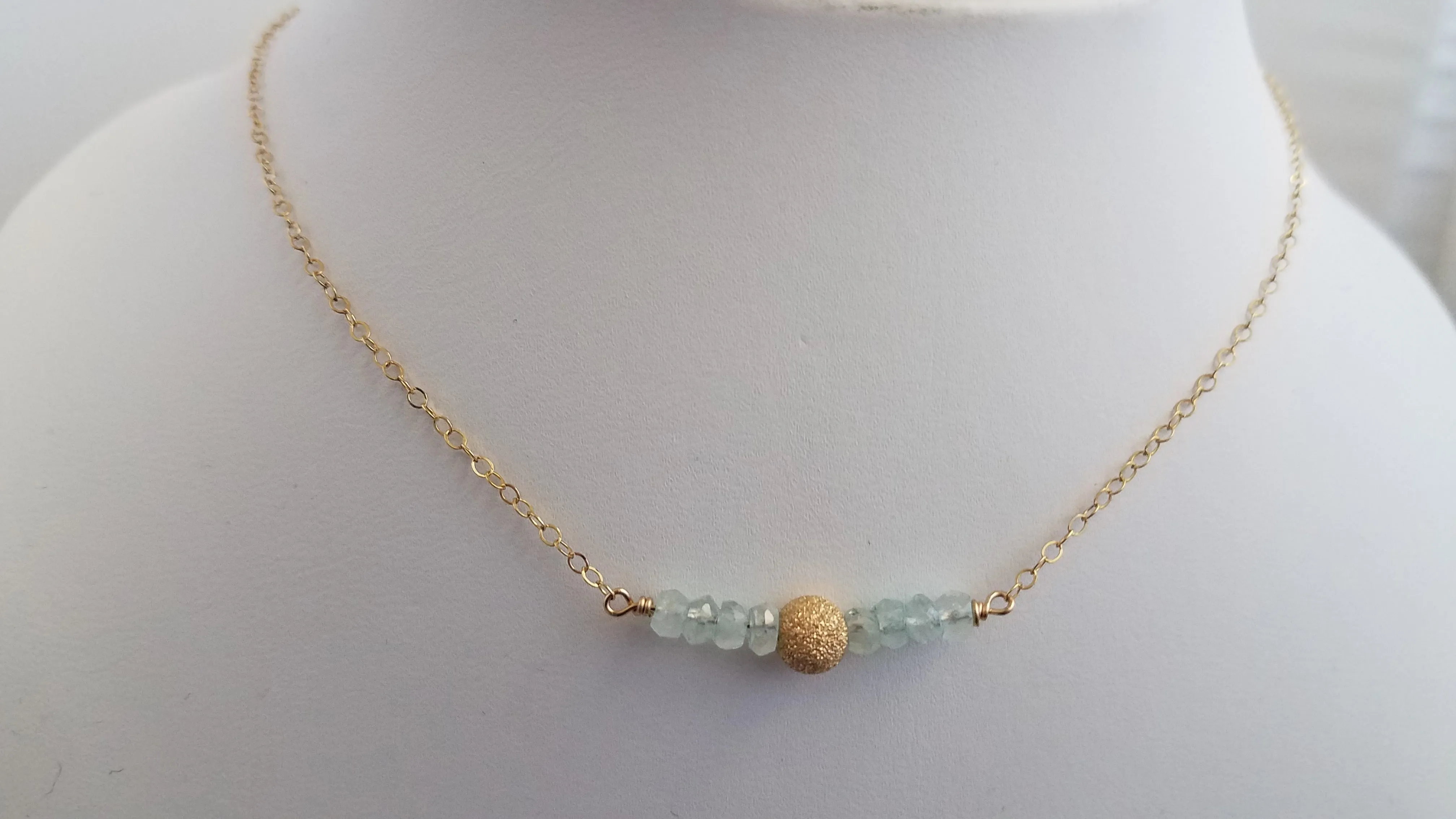 Delicate Bar Necklace Features Faceted Aquamarine Surrounded By a Gold Filled Sparkle Ball to Form a Curved Bar On Gold-Filled Chain Promote Calmness.