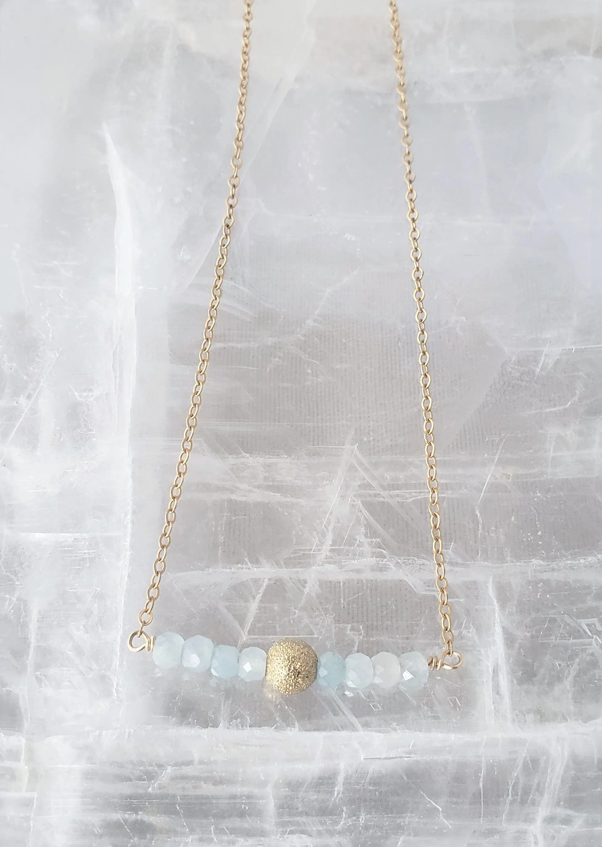 Delicate Bar Necklace Features Faceted Aquamarine Surrounded By a Gold Filled Sparkle Ball to Form a Curved Bar On Gold-Filled Chain Promote Calmness.